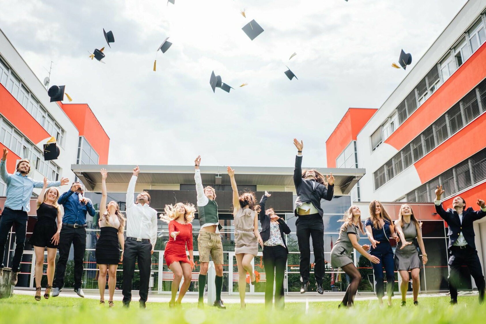 Studierende der FH Villach werfen bei der Abschlusszeremonie ihre Hüte in die Luft