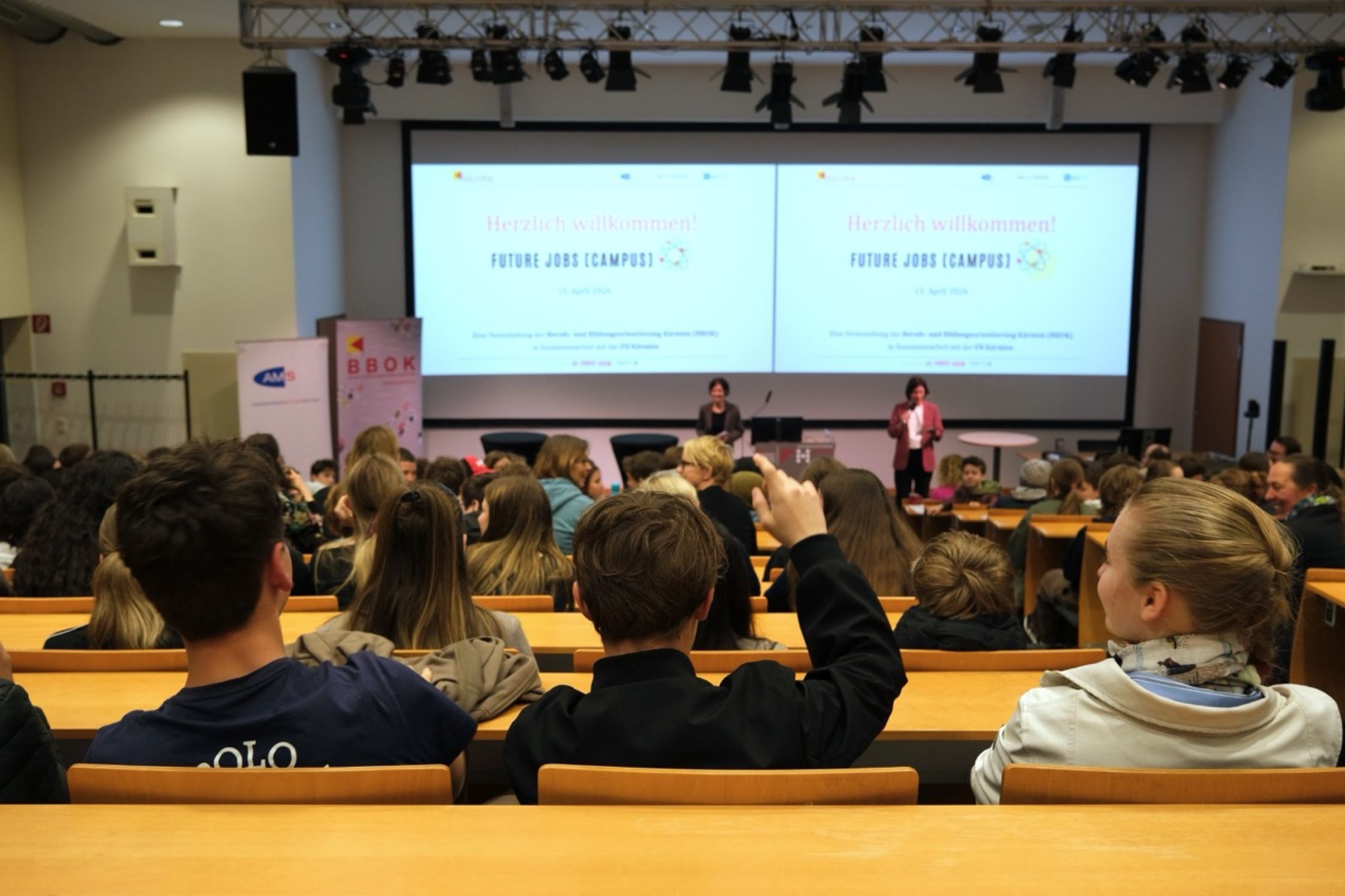Jugendliche sitzen im Audimax der FH Kärnten und zeigen auf