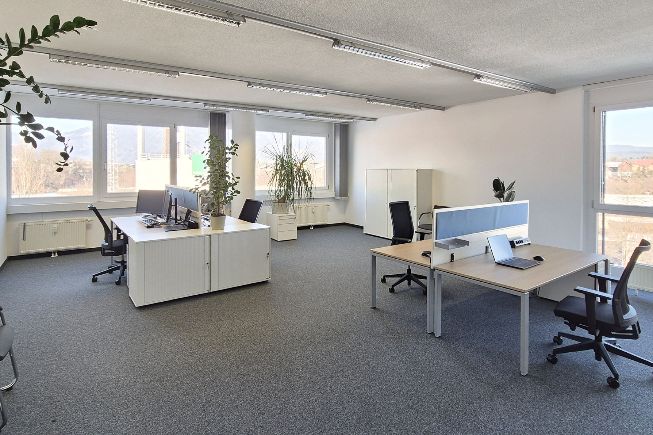 [Translate to Englisch:] Büroräumlichkeiten mit Schreibtischen und Standcomputern